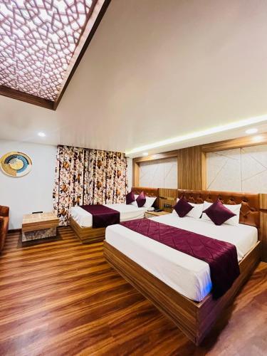 two beds in a room with wooden floors at Luxury stay at Hotel Broadway Boutique Mall Road Chowrasta Near Mahakal Temple in Darjeeling