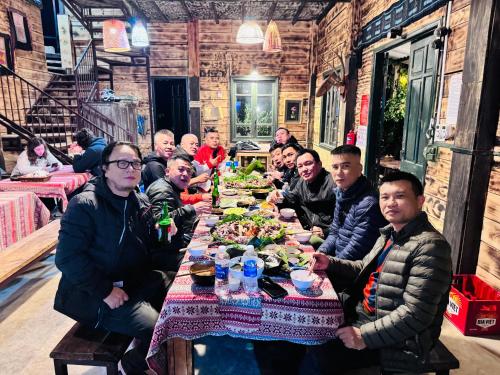 a group of people sitting at a table eating food at Du peak home in Làng Cac