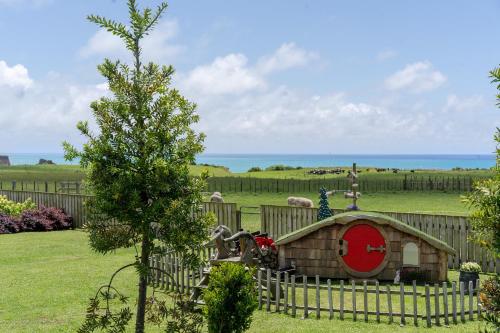 a wooden fence with a dog house in a yard at Onaeros Cute Little Cottages - Taranaki Retreat in Waitara