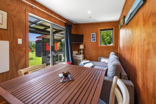a dining room with a wooden table and a couch at Onaeros Cute Little Cottages - Taranaki Retreat in Waitara