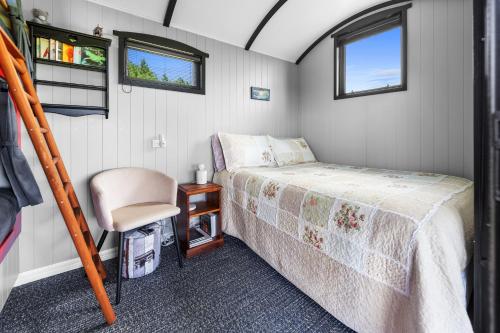 une petite chambre avec un lit et une chaise dans l'établissement Onaeros Cute Little Cottages - Taranaki Retreat, à Waitara