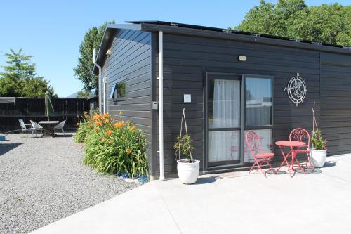 a black tiny house with chairs and a table at Marlborough Wine Country B&B in Blenheim