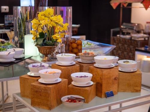 a buffet with bowls and flowers on a table at Hotel Royal Kuala Lumpur in Kuala Lumpur