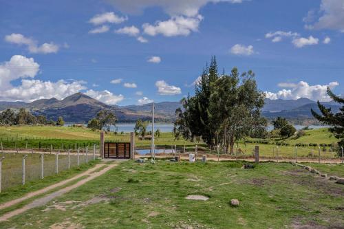 a field with a fence and a view of a lake at Granja Ecoturística Encuentros in Guatavita
