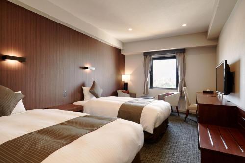 a hotel room with two beds and a flat screen tv at Hotel Azat Naha in Naha