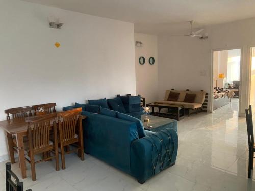a living room with a blue couch and a table at Den in Dehradun