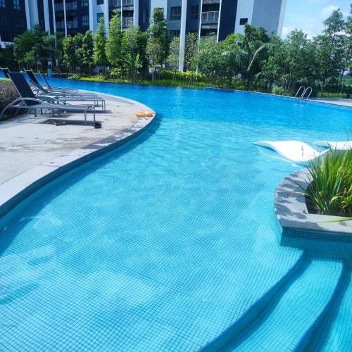 a large blue swimming pool with two lounge chairs at Umi SplashMania homestay in Banting