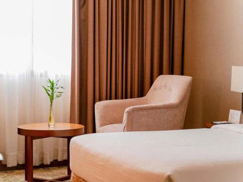 a room with a bed and a chair and a window at AURORA Hotel Plaza in Bien Hoa