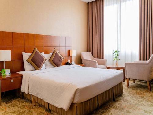 a hotel room with a large bed and two chairs at AURORA Hotel Plaza in Bien Hoa