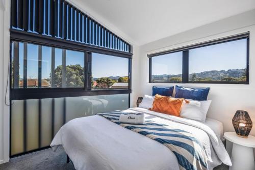 a bedroom with a bed and two large windows at Dreamcatcher Cottage - 2BR Mystic Moonrise in Lower Hutt