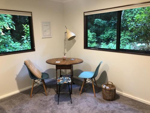a table and chairs in a room with two windows at Tranquil Studio in New Plymouth
