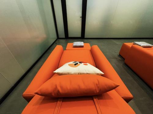 an orange couch with a pillow in a room at 사이공 트래블 라운지 Saigon Travel Lounge in Ho Chi Minh City