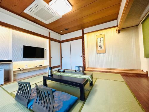a living room with a table and chairs and a tv at Hotel Takasago in Kochi