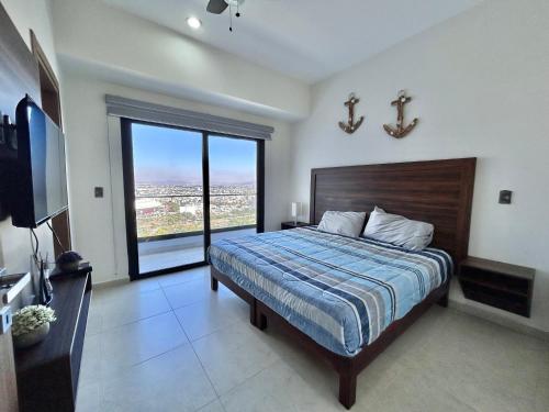 a bedroom with a large bed and a large window at Altomare hermoso depa con vista al mar in Mazatlán