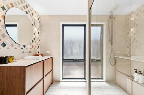 a bathroom with a shower and a sink and a mirror at Terra Palma - modern unit, aircon, walk to beach in Port Macquarie