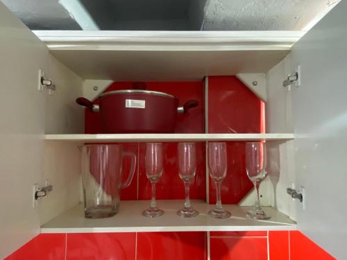 a cupboard with three wine glasses and a pot at Departamento familiar con vista al Chimborazo -Visite Riobamba in Riobamba
