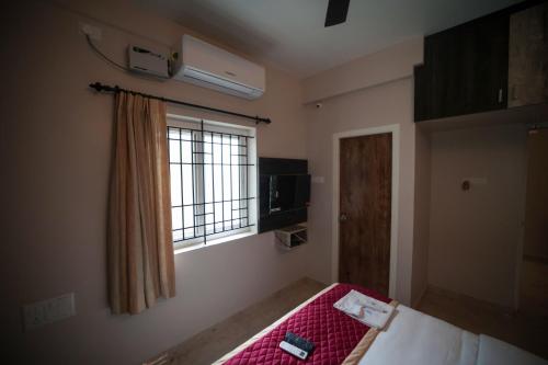 a small room with a bed and a window at Shanthi Service Apartment in Madurai