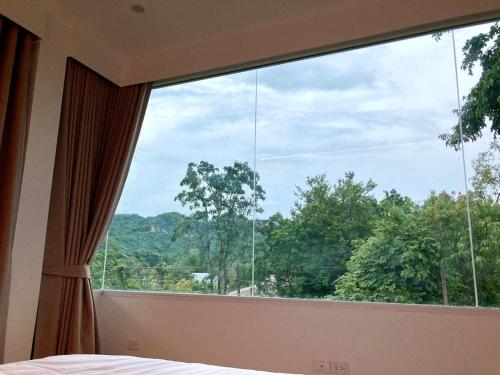 a bedroom with a large window with a view at The FAITH Khaoyai Valley in Ban Rai Khlong Sai