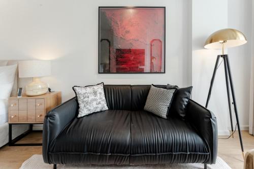 a black leather couch in a living room with a painting at The Zénith, By Harrys in Hanoi