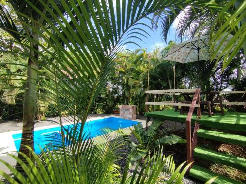 a swimming pool with a bench and an umbrella at Cabaña YeyYe in San Ramón