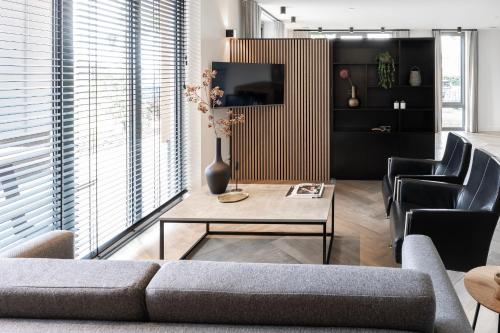 a living room with a couch and a table and chairs at Xl Newly Built Nature Villa, Wifi in Ledeacker