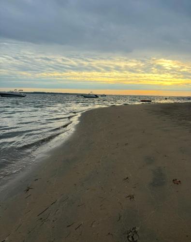 une plage de sable avec deux bateaux dans l'eau dans l'établissement Maison cap ferret proche des plages, à Lège-Cap-Ferret