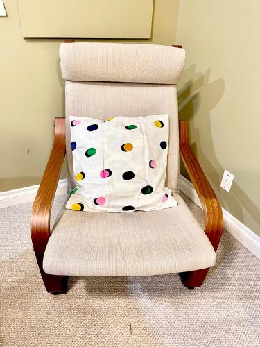 a chair with a polka dot pillow on it at Cozy Walkout suite with King bed, Kitchen, Parking & Patio in Calgary