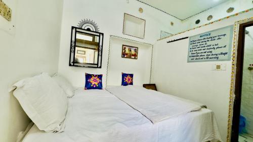 a bedroom with a bed with white sheets and a mirror at Hotel White House - A Family Homestay in Pushkar