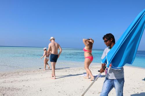 a group of people standing on a beach at Liberty Guesthouse Maldives in Mahibadhoo