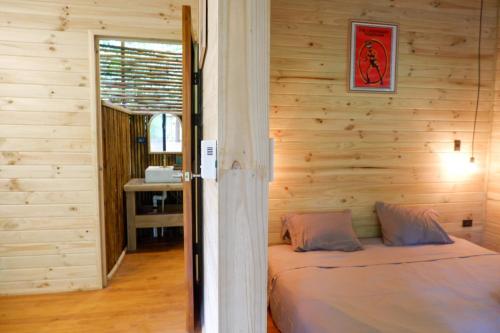 a bedroom with a bed in a wooden wall at Rainbow Lodge Costa Rica in Savegre