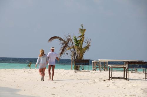 a man and a woman walking on the beach at Liberty Guesthouse Maldives in Mahibadhoo