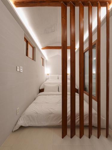a bedroom with white walls and a bed with wooden posts at Bukchon Hanok - 'Yul Jae' The access code is sent by message in Seoul