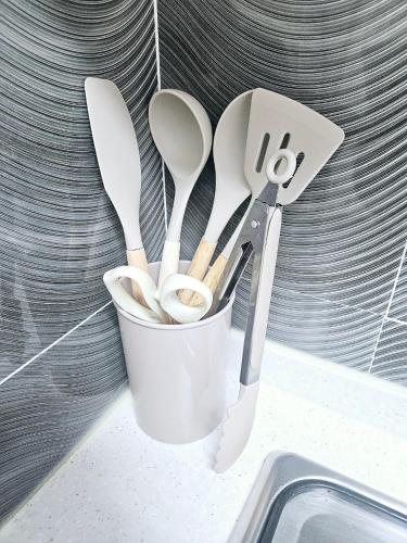 a cup filled with spoons and spatulas next to a sink at 로맨틱 프라이빗 테라스, 무료주차, 2룸 in Daegu