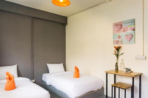 two beds with orange pillows in a room at Love CNX Guesthouse in Chiang Mai