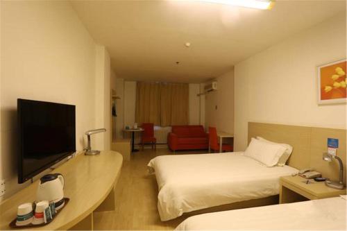 a hotel room with two beds and a flat screen tv at Jinjiang Inn Qingdao Bus Station in Qingdao