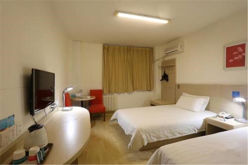 a hotel room with two beds and a flat screen tv at Jinjiang Inn Qingdao Bus Station in Qingdao
