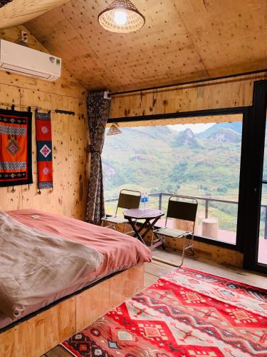 a bedroom with a bed and a table and a large window at Du peak home in Làng Cac
