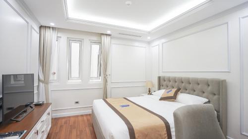 a bedroom with a bed and a desk and a television at Luxe Paradise Residence 79 Nguyen Du in Hanoi