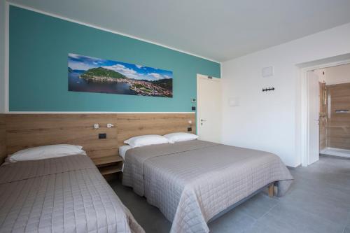 a bedroom with two beds and a painting on the wall at La Guest House di PIAZZA MOTTA in Albese Con Cassano