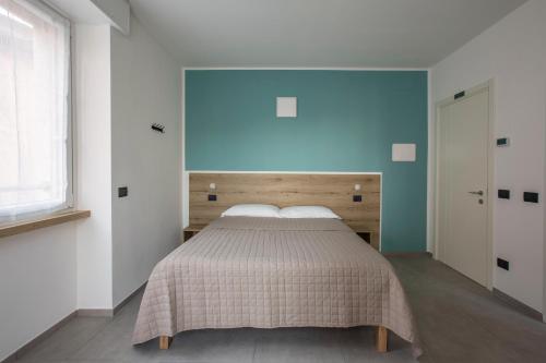 a bedroom with a bed with a blue wall at La Guest House di PIAZZA MOTTA in Albese Con Cassano