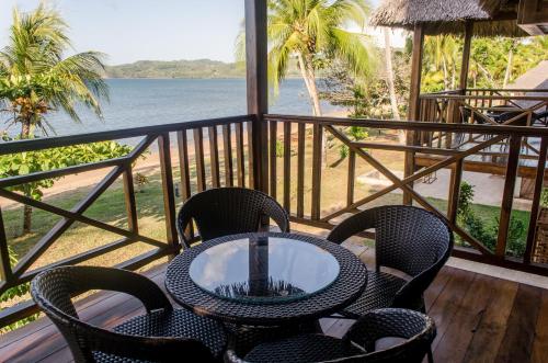 a table and chairs on a balcony with a view of the ocean at Home The Residence in Befotaka Bay