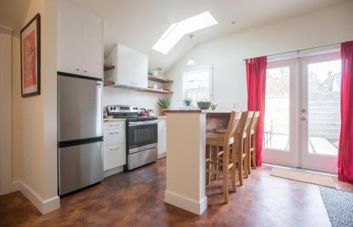 a kitchen with a refrigerator and a table with chairs at Cozy Alley Cottage, Concordia, Alberta Arts, NE PDX in Portland