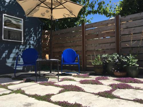 a patio with two chairs and an umbrella and flowers at Cozy Alley Cottage, Concordia, Alberta Arts, NE PDX in Portland
