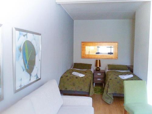 een kleine kamer met 2 bedden en een bank bij Apartment Kukkarokivenkatu in Mänttä