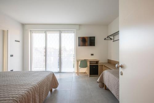 a bedroom with two beds and a desk and a window at La Guest House di PIAZZA MOTTA in Albese Con Cassano