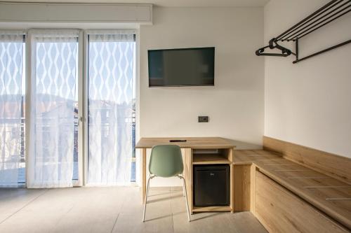 a room with a desk with a television and a chair at La Guest House di PIAZZA MOTTA in Albese Con Cassano
