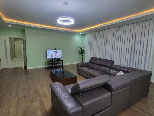 a living room with a leather couch and a tv at Apartment 6, Turquaz residence in Accra