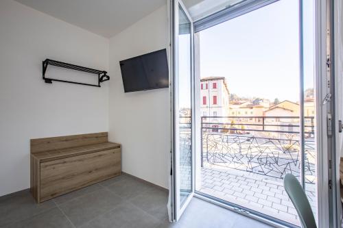 a room with a balcony with a tv and a sliding glass door at La Guest House di PIAZZA MOTTA in Albese Con Cassano