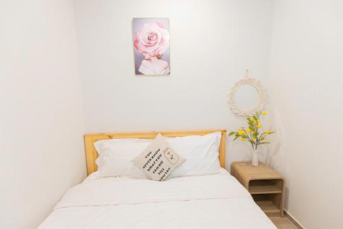 a bedroom with a bed with white sheets and a pink rose at The Sóng Vũng Tàu- SAO VIỆT Căn Hộ Nghỉ Dưỡng 5 Sao in Vung Tau
