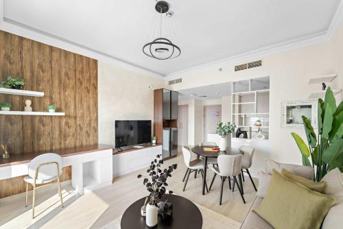 a living room and kitchen with a table and chairs at Silkhaus Canalside 1BR at Water's Edge in Yas Island in Abu Dhabi